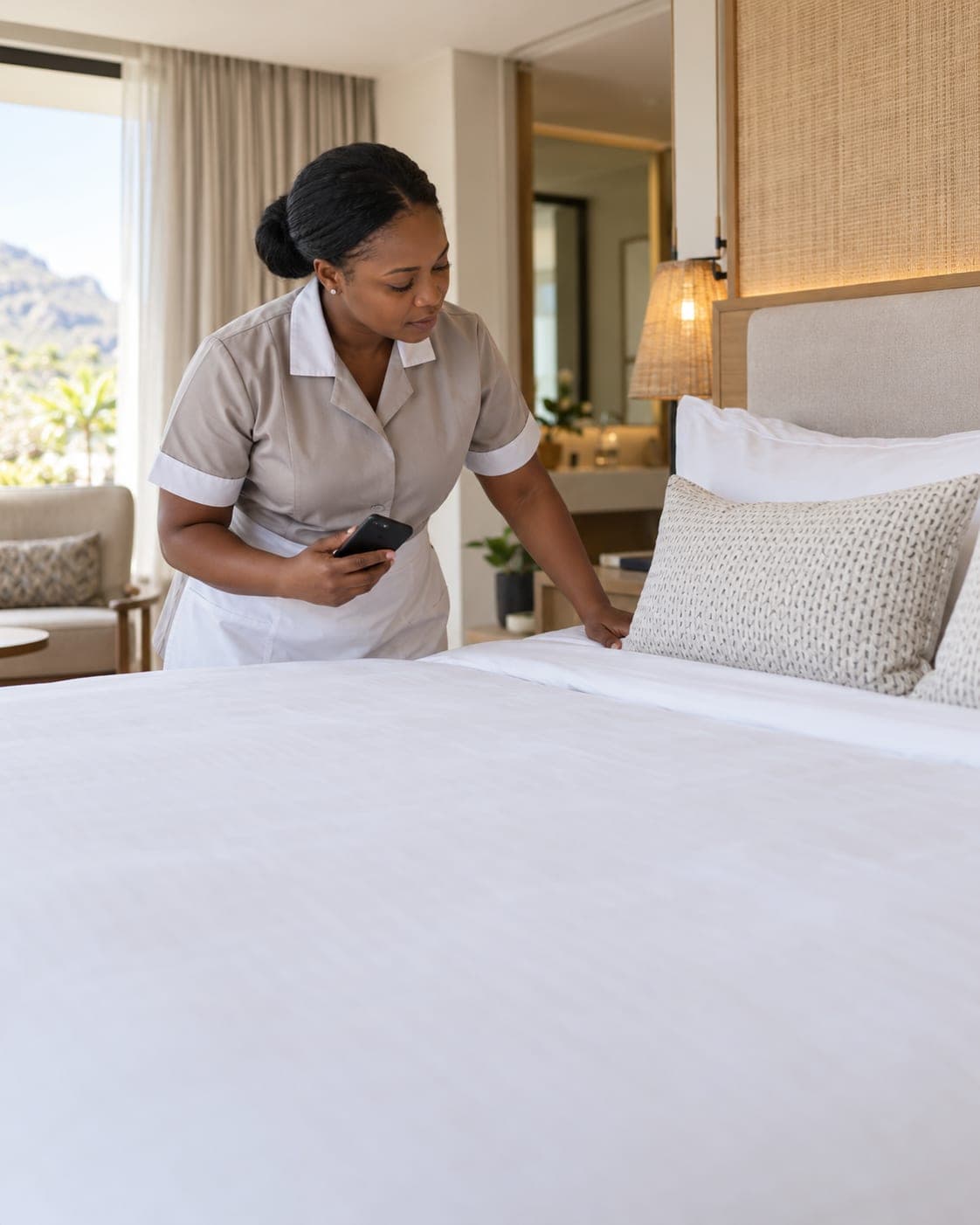 A housekeeping supervisor inspects a freshly made bed.