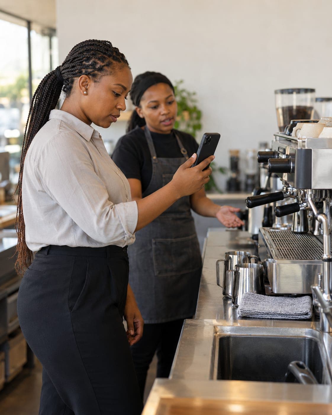 An area manager photographs the espresso station while a barista explains.